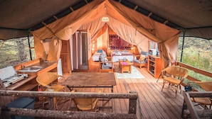 Une tente confortable dotée d’un coin cuisine, de meubles en bois et offrant une vue sur l’extérieur.