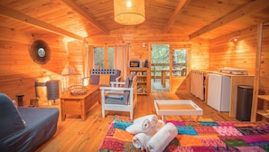 L’intérieur d’un chalet en bois chaleureux et accueillant, avec un canapé, une courtepointe, une table à manger et un coin cuisine.
