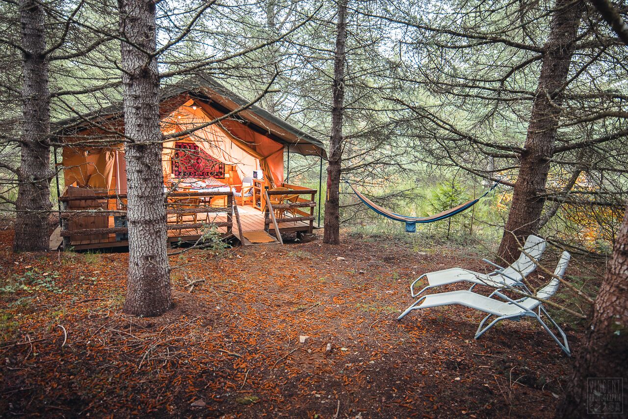 A rustic cabin with a wooden deck and a hammock.