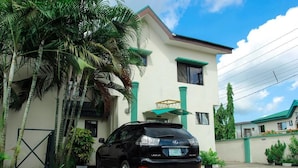 A black Lexus SUV parked in front of a two-story building with green trim and a balcony. - Sweet Dreams Hotel (Calabar)