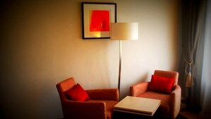 A room with two orange armchairs, a small table, a floor lamp, and a framed picture on the wall. - Sweet Dreams Hotel (Calabar)