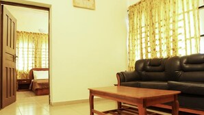 A living room with a black leather sofa, a wooden coffee table, and a bed with a brown headboard. - Sweet Dreams Hotel (Calabar)