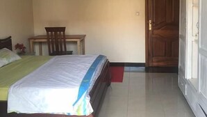 A bedroom with a bed, a chair, a small table, and a wardrobe. - Nova Apartment (Kigali)