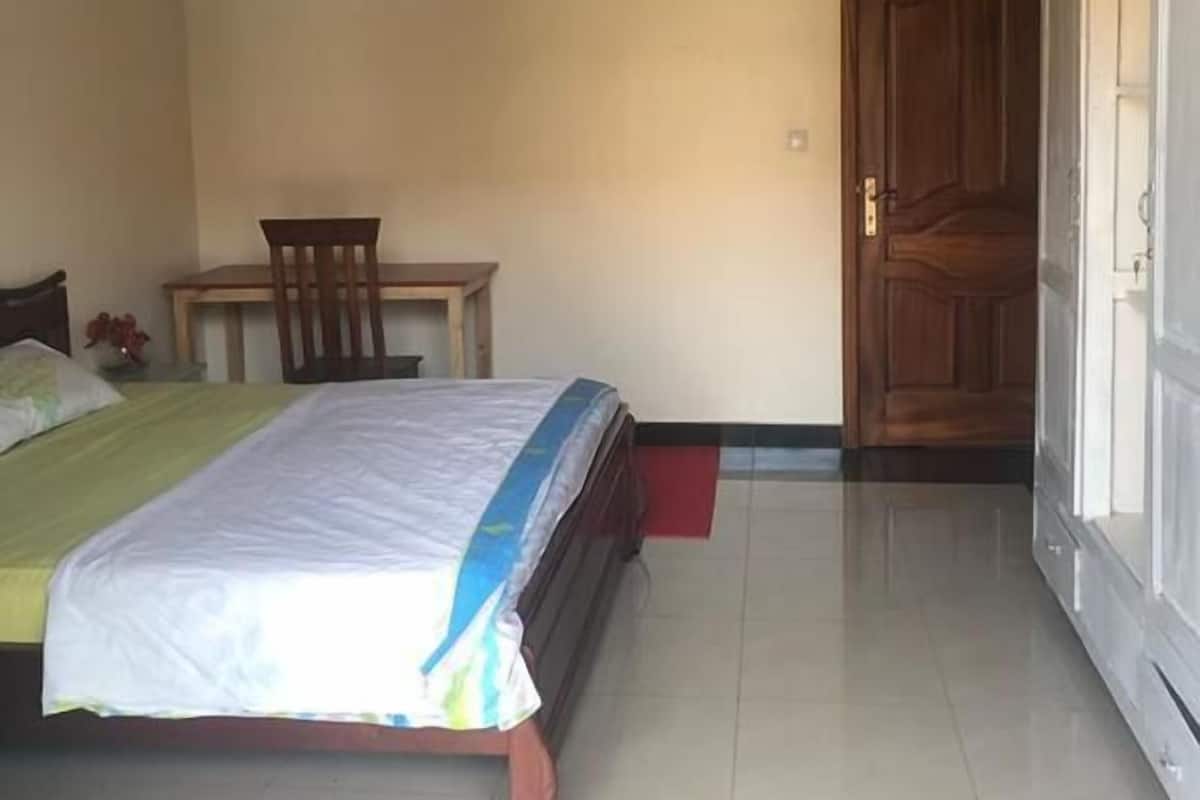A bedroom with a bed, a chair, a small table, and a wardrobe.