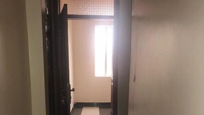 A narrow hallway with a tiled floor leading to a room with a window. - Nova Apartment (Kigali)