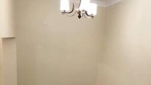 A dining area with a long table, chairs, and a chandelier. - Nova Apartment (Kigali)