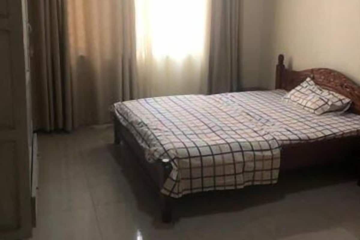 A bedroom with a bed, curtains, and a wooden door.