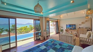 A spacious room with a large sliding glass door leading to a balcony with a view of the sea and mountains. - Soul Villas By The Beach - Phuket (Wichit)