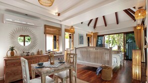 Una habitación amplia con zona de comedor, una cama y un ventanal grande.