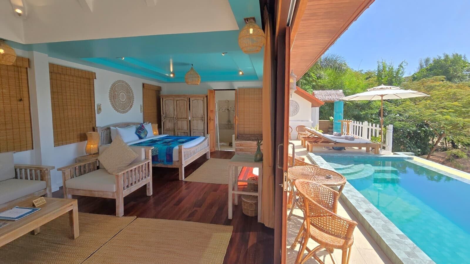 Un dormitorio con cama, sofá y una mesita. Cuenta con un ventanal y vistas a una piscina.