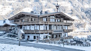 A multi-story hotel with a wooden facade, balconies, and a mountain backdrop. - Secluded Farmhouse in Tyrol near Ski Area (Schwendau)
