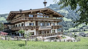 A multi-story building with balconies, a tower, and a view of a mountainous landscape. - Secluded Farmhouse in Tyrol near Ski Area (Schwendau)