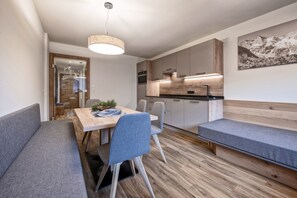 A compact kitchen with wooden cabinets, a dining table with chairs, and a bench.