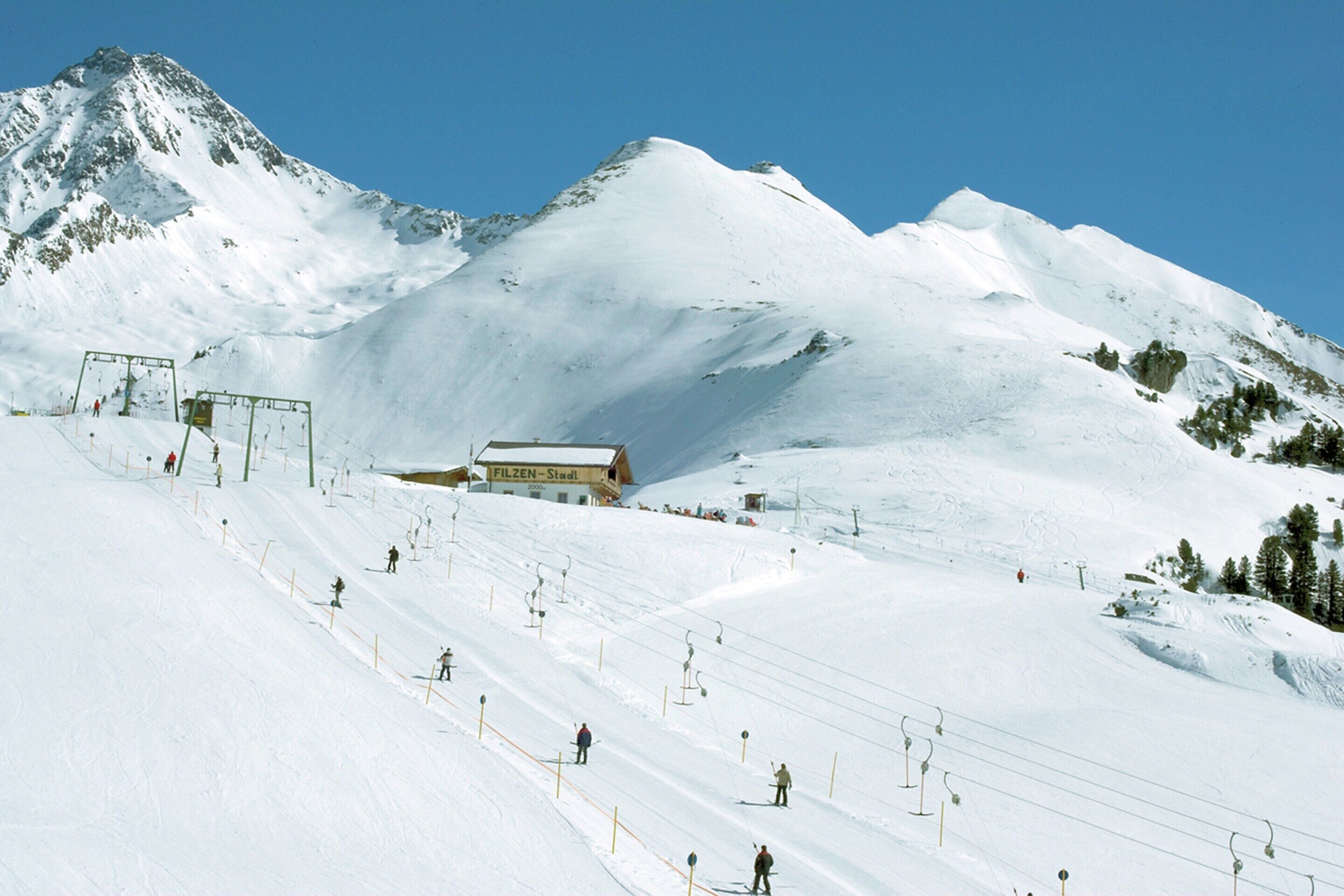 Pista da sci innevata con un edificio con la scritta "FILZEN-Stadl" sullo sfondo.