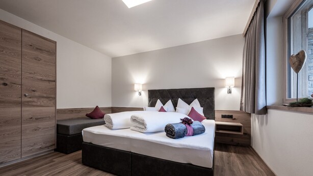 A modern bedroom with a large bed, bedside tables, a wardrobe, and a window with curtains. - Secluded Farmhouse in Tyrol near Ski Area (Schwendau)