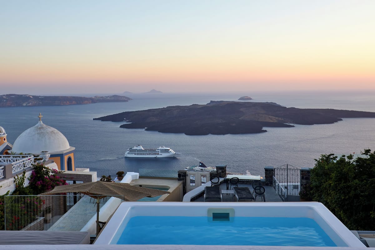 A pool area with a view of the sea and a cruise ship in the distance.