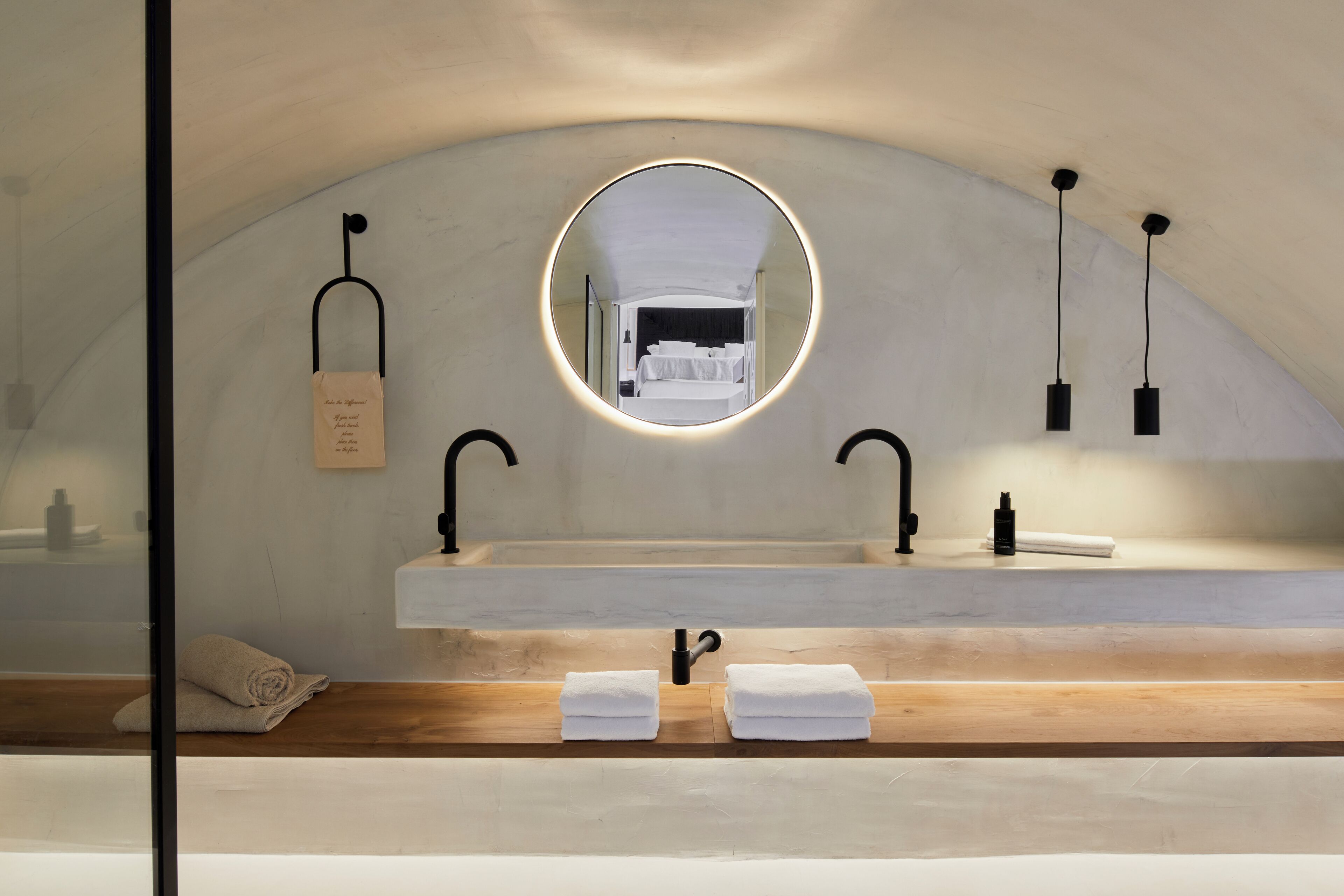 A modern bathroom with a large mirror, two sinks, and a wooden vanity.
