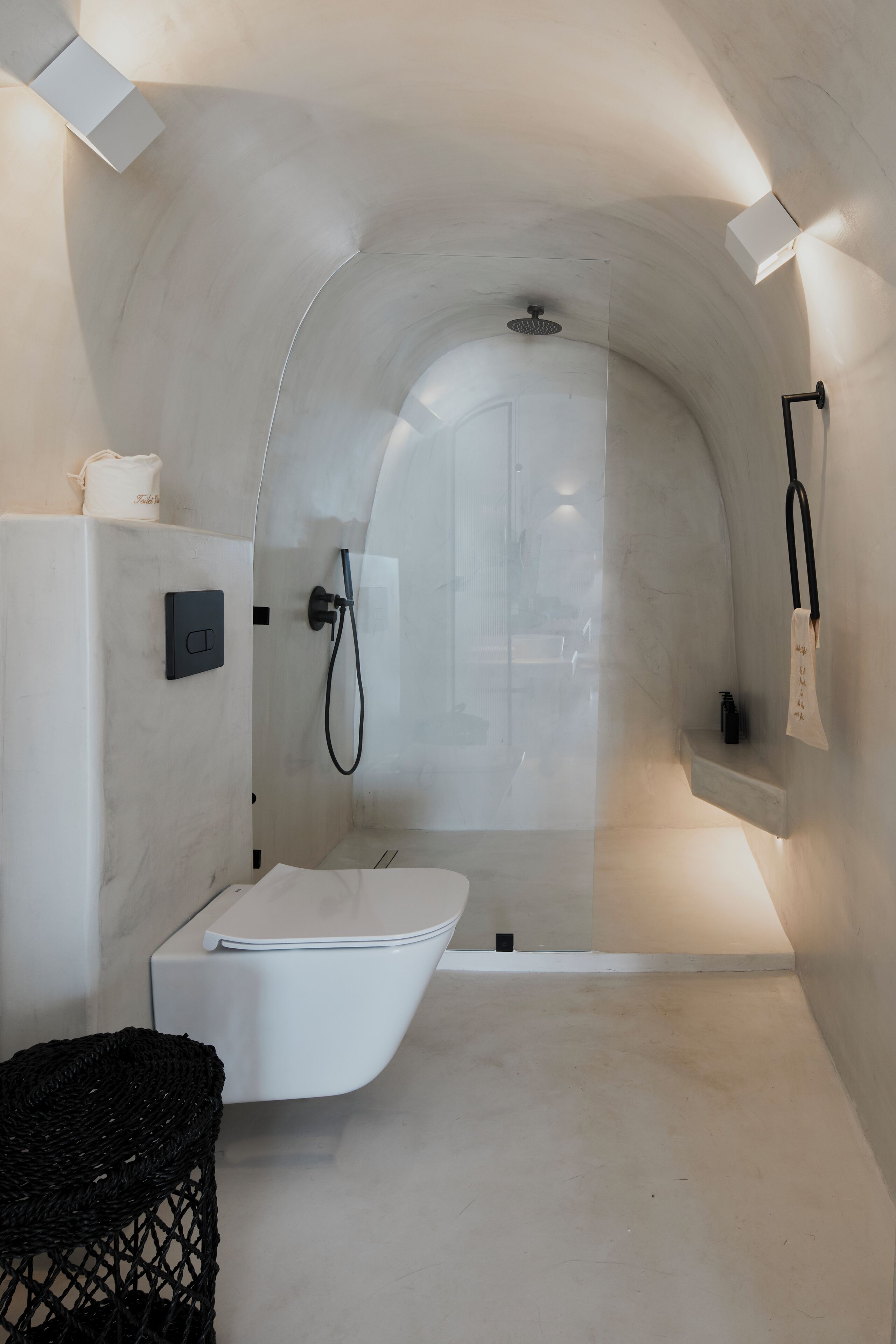 A modern bathroom with a curved ceiling, a built-in shower, and a white vanity.