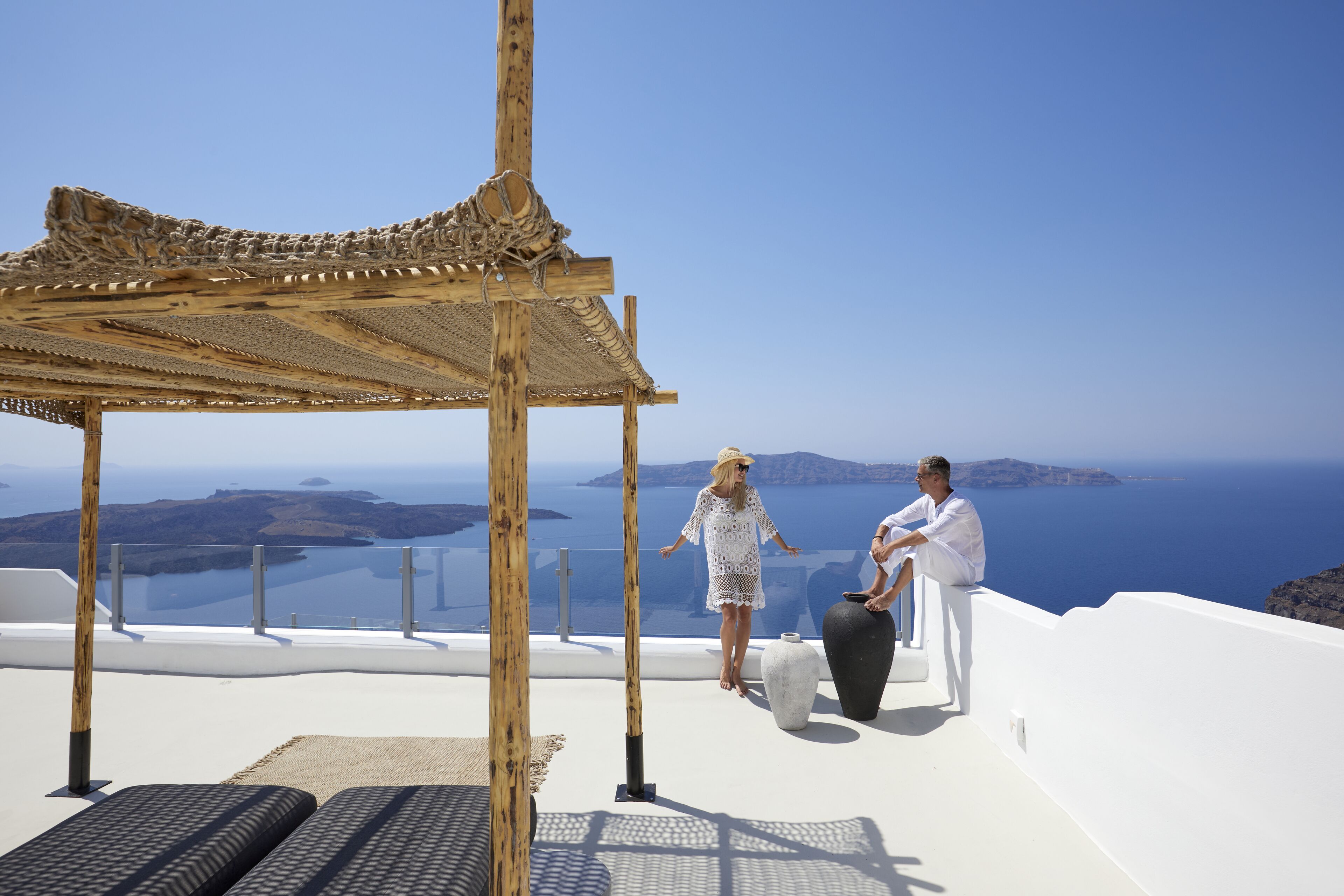 A couple on a rooftop terrace with a view of the sea and islands.