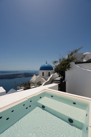 Piscina no terraço com vista ampla para um edifício de cúpula azul e o mar.