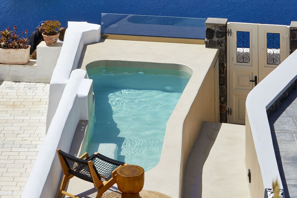 A large cruise ship docked near a coastal area with a pool and lounge area.