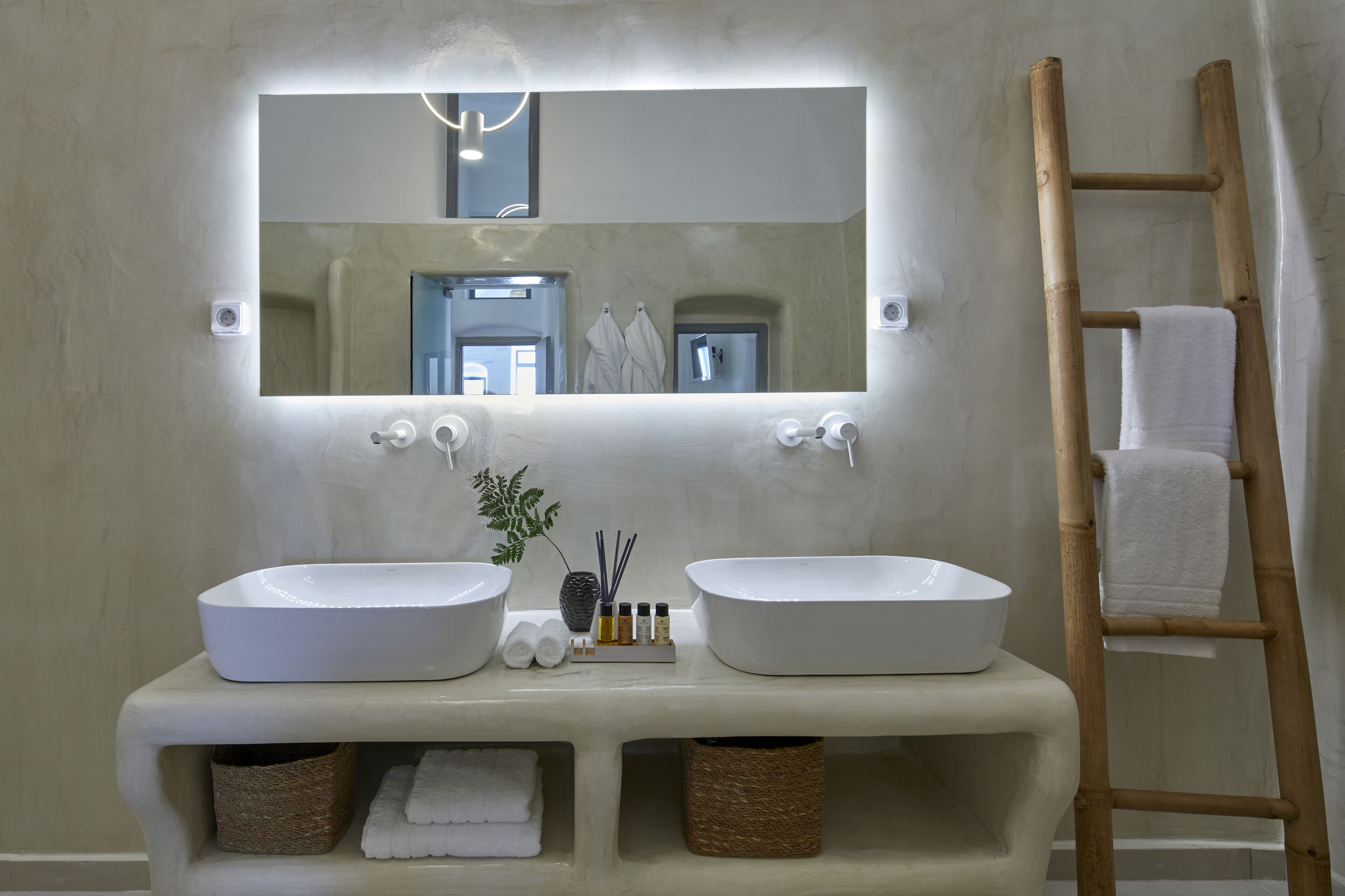 Une salle de bain avec deux lavabos, un miroir et une échelle en bois.