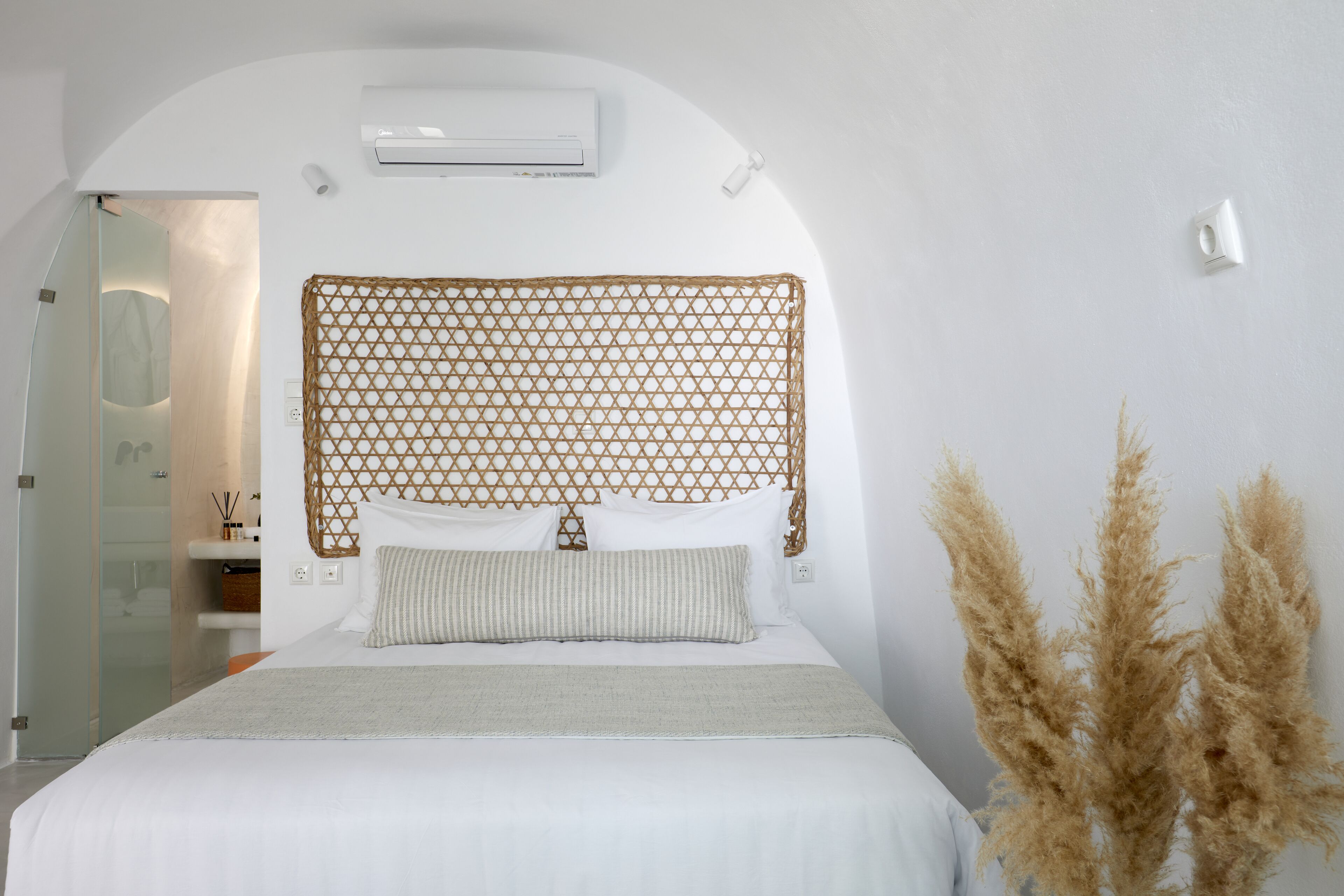 A bedroom with a bed, a headboard, a bedside table, and a wall-mounted air conditioner.