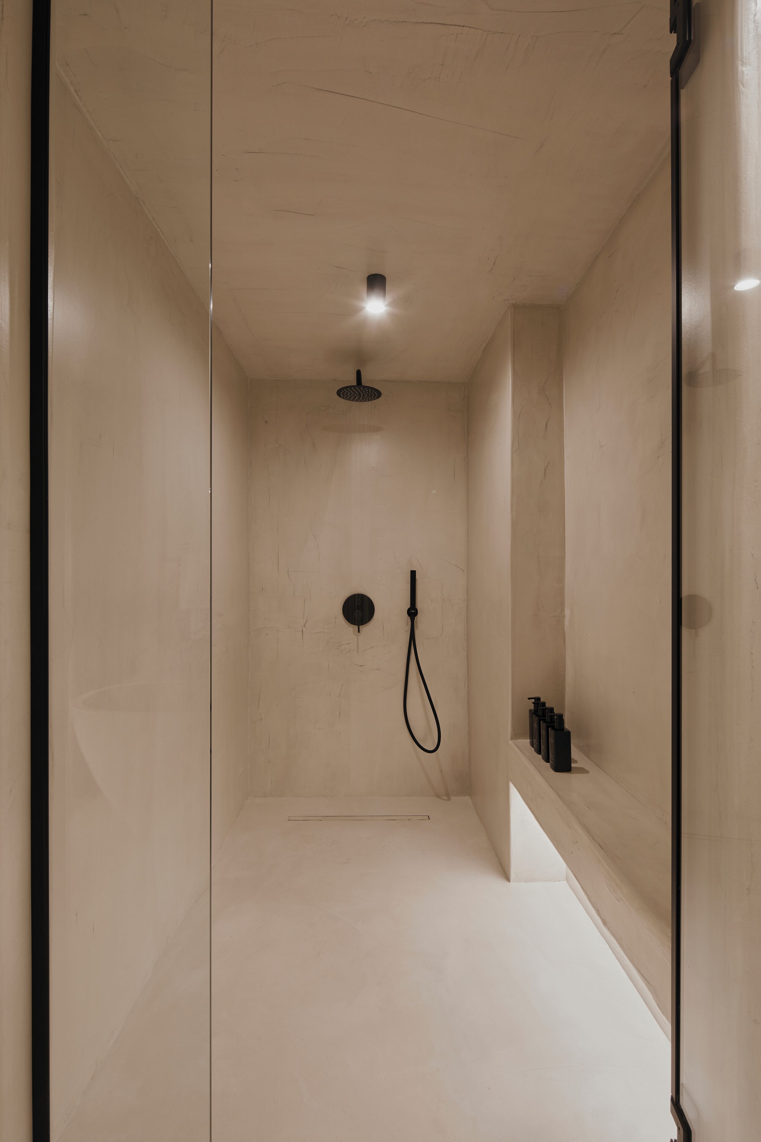 A modern shower area with a handheld showerhead and a fixed showerhead on the ceiling.