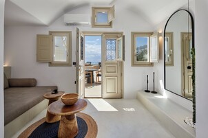 Un interior moderno con sofá, mesas de madera y vistas a través de un ventanal abierto.