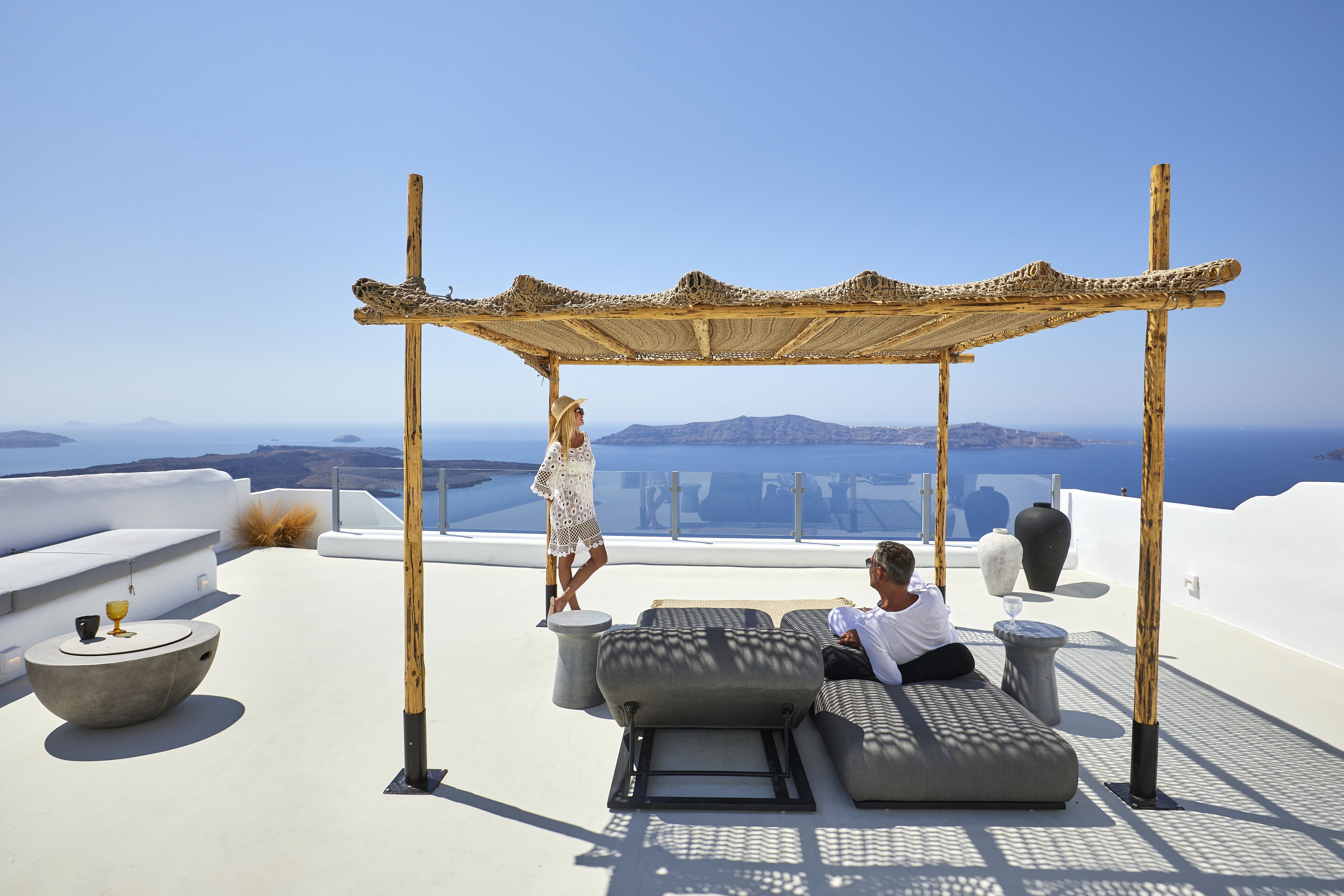 Une terrasse sur le toit agrémentée d’une pergola en bois, de coins salon confortables et offrant une vue sur la mer.