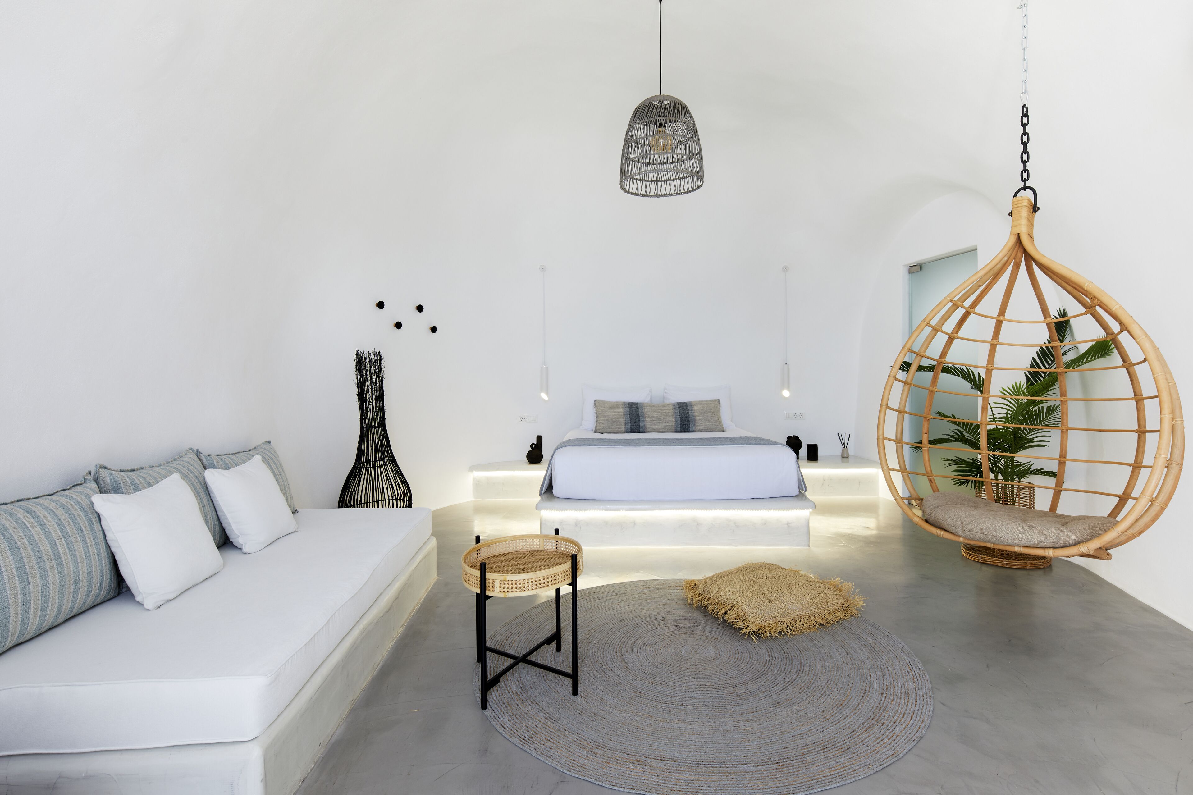 A modern bedroom with a hanging chair, a bedside table, and a bed with a blue headboard.