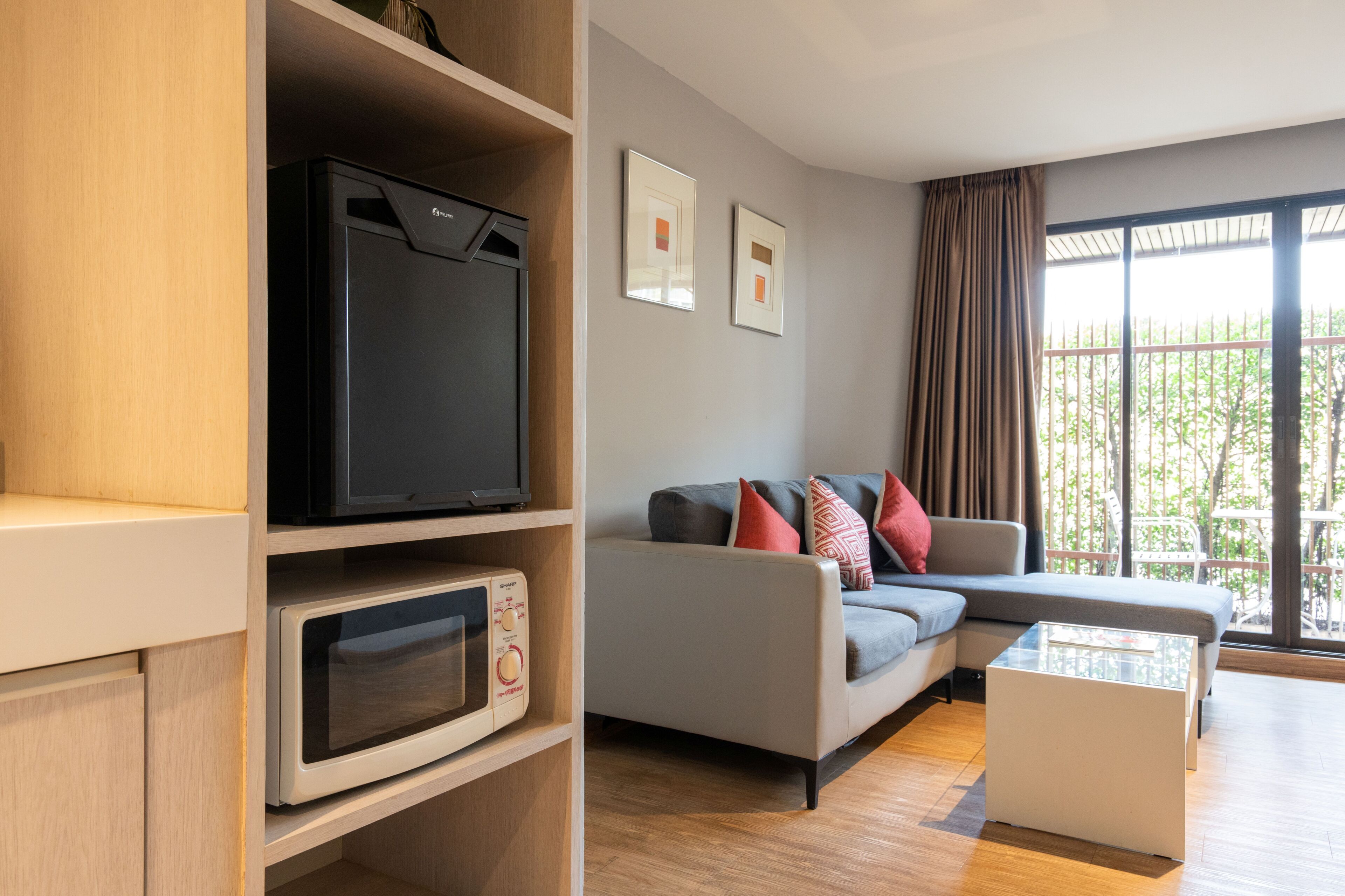 Ein modernes Wohnzimmer mit Flachbildfernseher, Mikrowelle, einer gepolsterten Couch, einem Couchtisch und einem großen Fenster mit Blick.