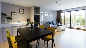Un appartement moderne comprenant un coin repas, un salon avec un canapé et un balcon aménagé avec du mobilier d’extérieur.