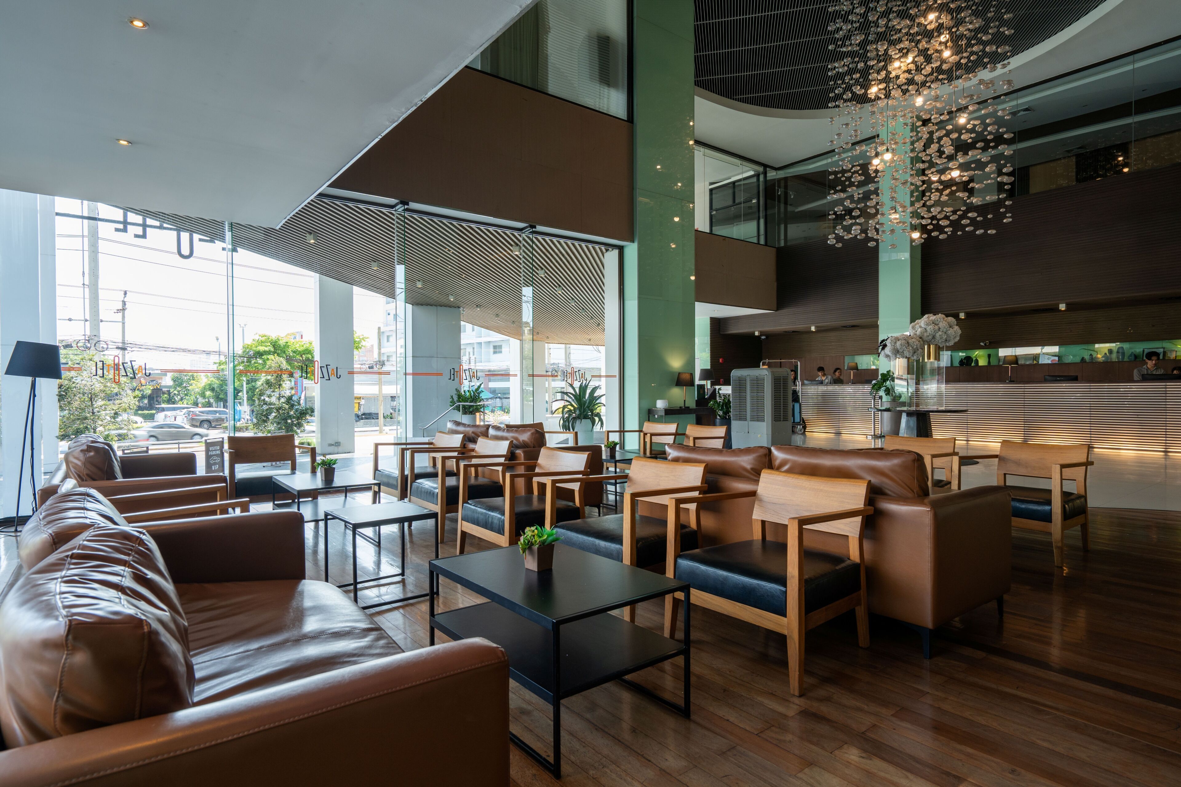 A modern lobby with leather seating, a reception desk, and a large chandelier.
