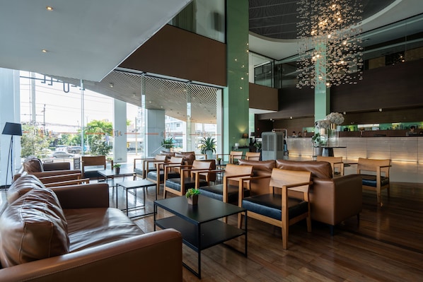 A modern lobby with leather seating, a reception desk, and a large chandelier.