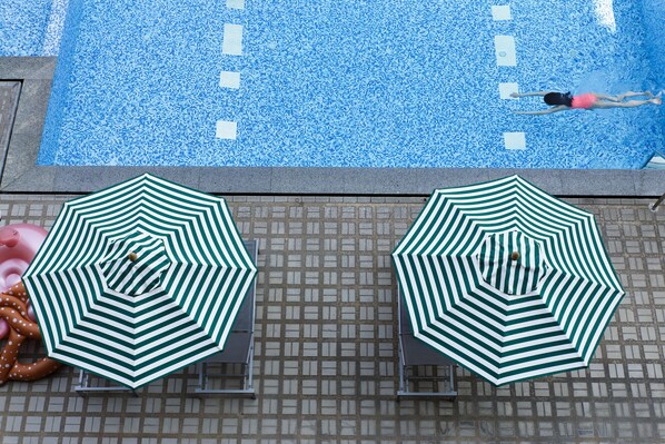 A swimming pool with two green and white striped umbrellas and a pool float. - Jazzotel Bangkok (Bangkok)