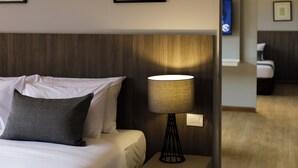 Une chambre d’hôtel avec un lit, une table de chevet avec une lampe et des tableaux encadrés au mur.