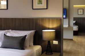 Une chambre d’hôtel avec un lit, une table de chevet avec une lampe et des tableaux encadrés au mur.