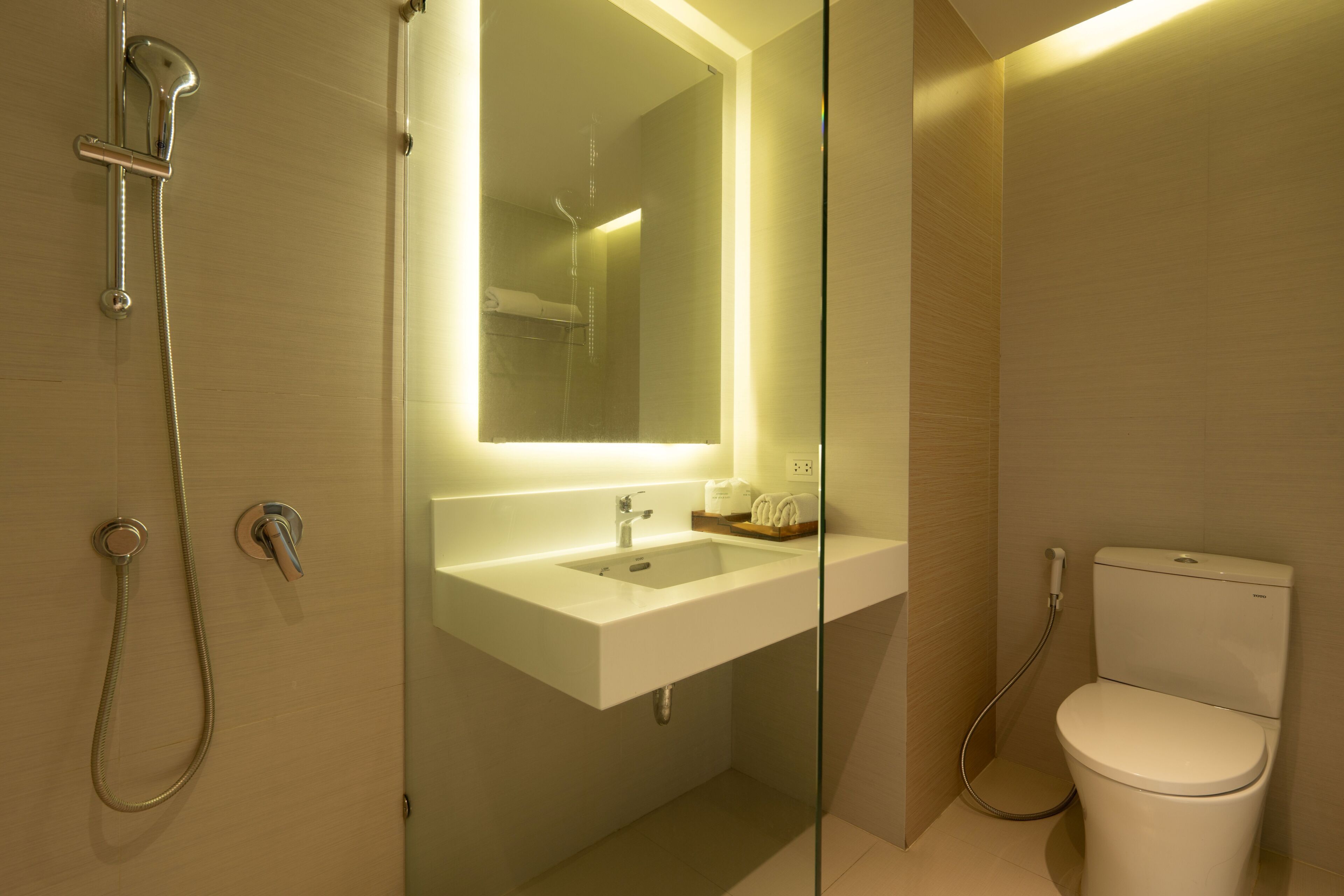 A modern bathroom with a glass-enclosed shower, a white sink, and a toilet.