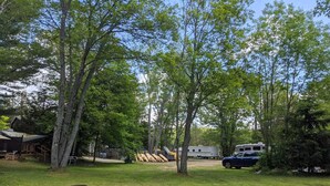 A campground with RVs, a wooden deck, and a picnic table. - Modern Rental Trailer at Bon Echo Family Campground (The Prowler) (Cloyne)