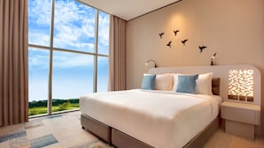 A modern hotel room with a large bed, a nightstand, a wall-mounted light, and a view of the outdoors. - The District Hotel (Dubai)