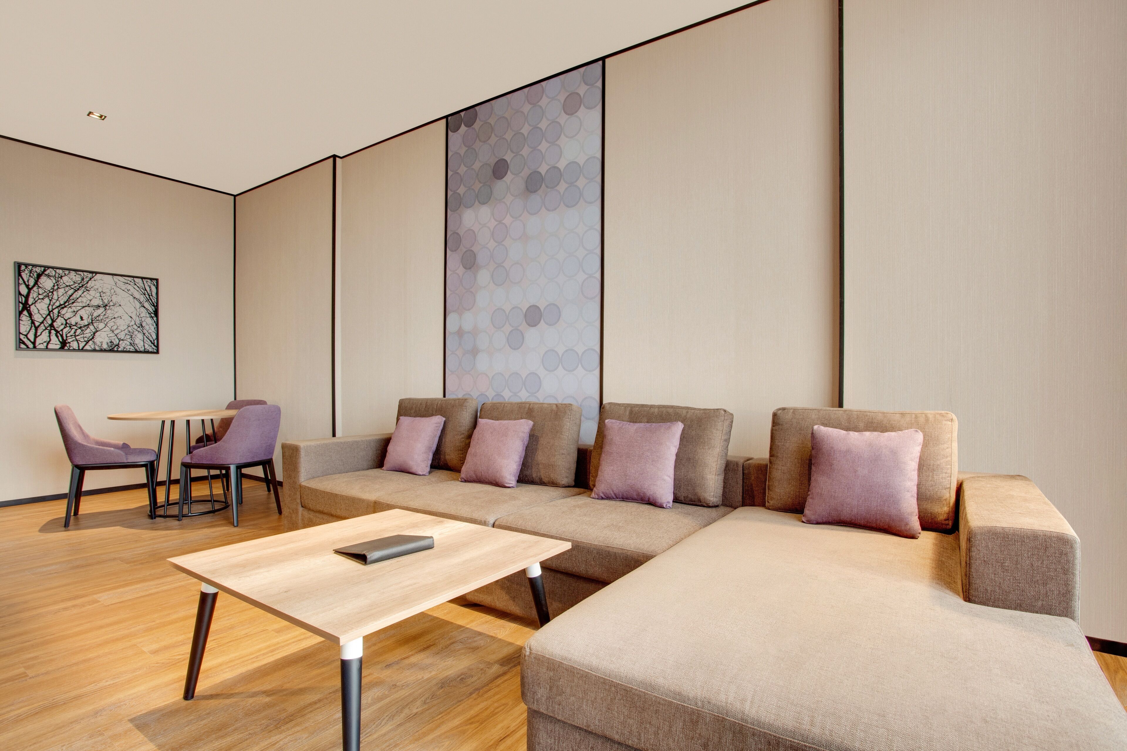 Un salon moderne avec un canapé d’angle, une petite table et des fauteuils violets.