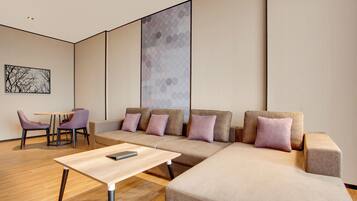 Un salon moderne avec un canapé d’angle, une petite table et des fauteuils violets.