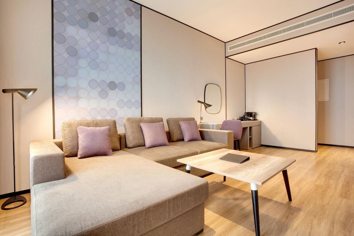 A modern living room with a sectional sofa, a small table, and a desk.