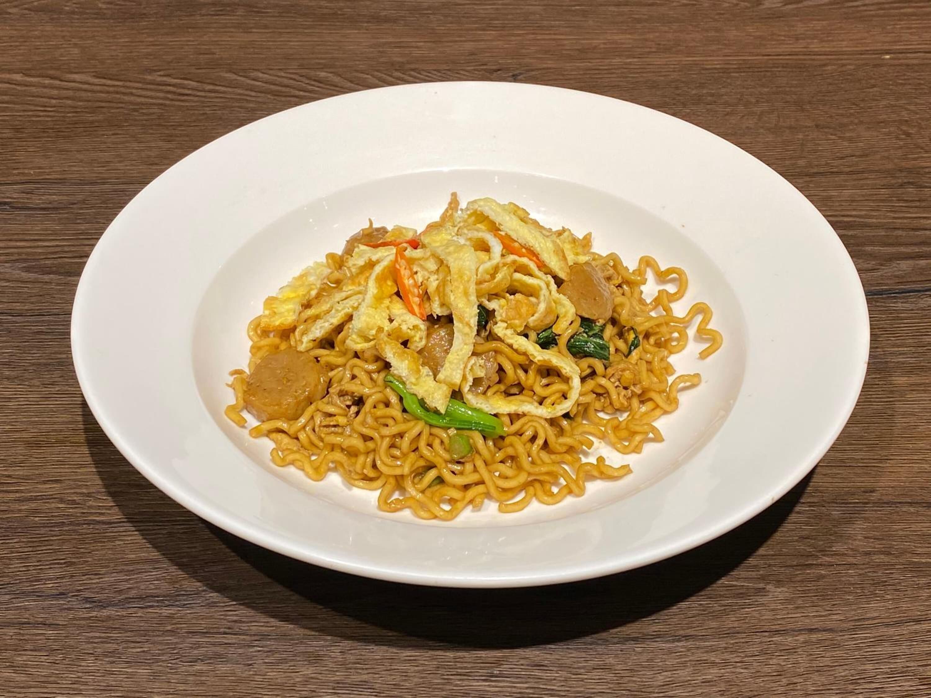 A plate of stir-fried noodles with vegetables and scrambled eggs on a white plate.