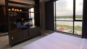 A hotel room with a large bed, a TV on a wooden stand, and a view of a river.