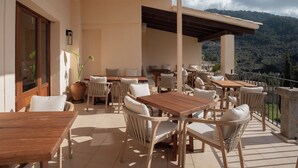 A covered outdoor seating area with tables and chairs, overlooking a mountainous landscape. - Marton Turisme de Interior (Valldemossa)