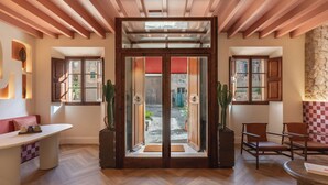 A spacious room with a wooden floor, a large window, and a door leading outside. - Marton Turisme de Interior (Valldemossa)