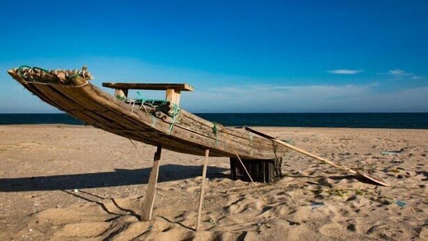 A wooden boat on a sandy beach with a clear blue sky in the background. - Maqueda @ Mozambique (Manhica)