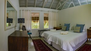A bedroom with a large bed, a desk, a chair, and a window with curtains. - Maqueda @ Mozambique (Manhica)